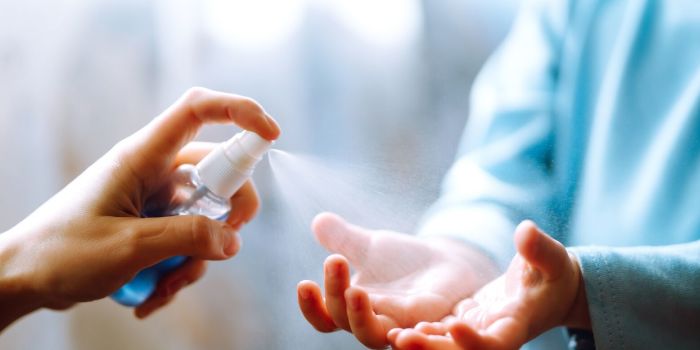 person spraying hand sanitiser on a child's hand