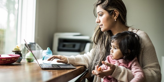 woman with a baby on lap checking laptop