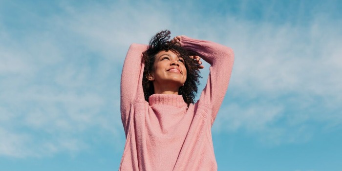 happy woman looking up at the blue sky