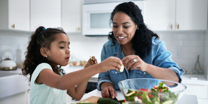Adult cooking courgettes with a toddler