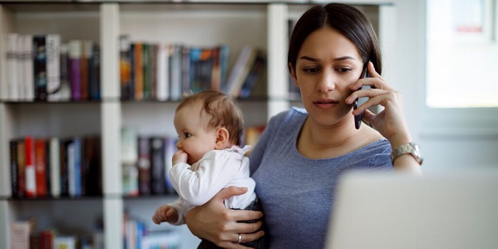 mum on the phone and laptop with baby on lap