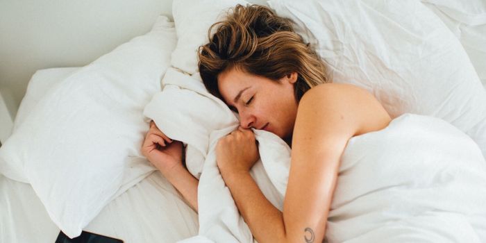 woman sleeping in bed with phone next to her