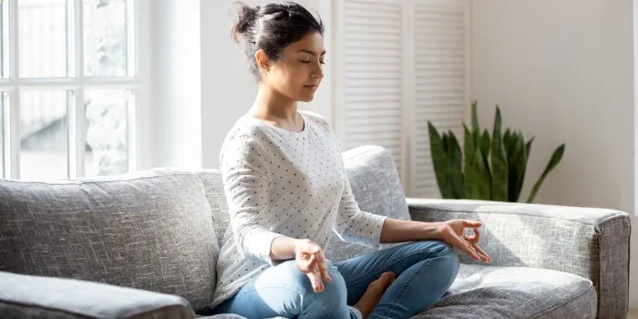 a woman meditating on the sofa