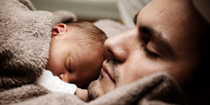 new born baby sleeping on father's chest