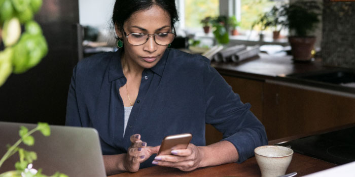 woman working on a laptop and messaging on mobile