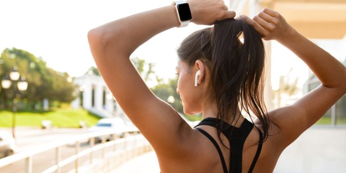 woman pausing to tie her hair while running