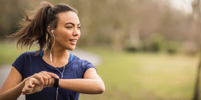 woman running outdoors and looking at her fitbit