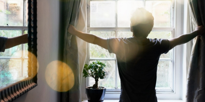 person opening curtains and stretching standing near the window
