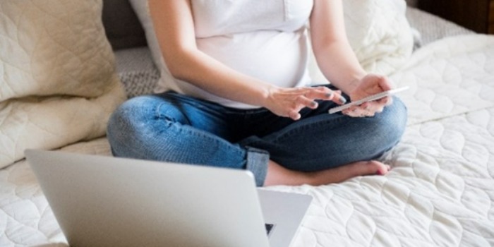 pregnant woman on the phone in bed