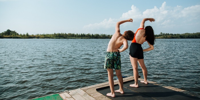 adult and child exercising by the sea