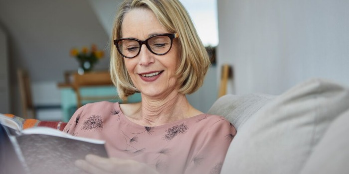 person with a pink top reading a book indoors
