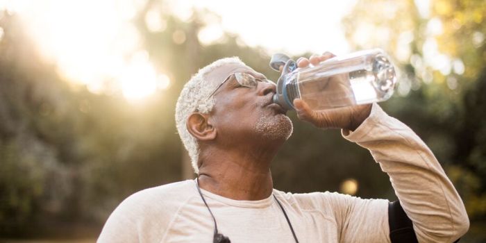 person walking outdoors, drinking water from a bottle