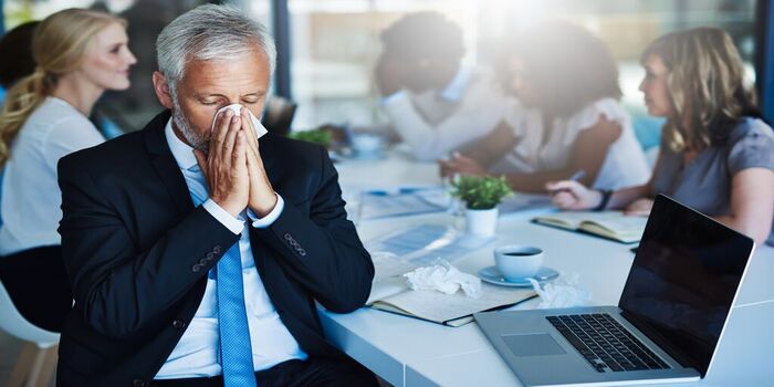 A person in a blue tie blowing their nose