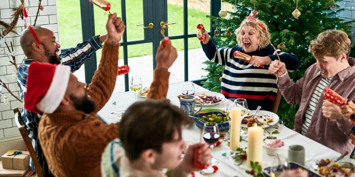 group of people pulling crackers around a Christmas meal