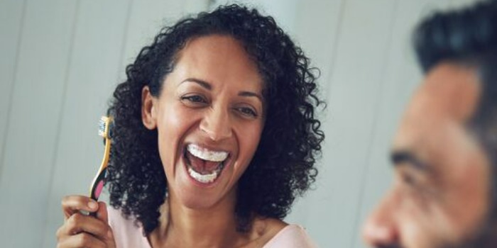 two people laughing while brushing teeth