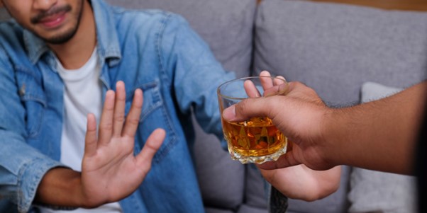 person saying gesturing no to an alcoholic drink