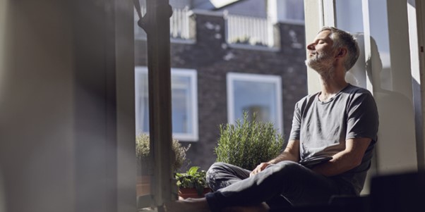 person relaxing by the window looking at the sun shine