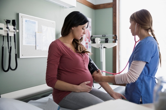 A pregnant woman having her blood pressure taken by a nurse