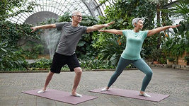 Two adults doing a stretching or yoga pose together outdoors