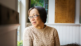 Older adult sitting by a window, looking outside