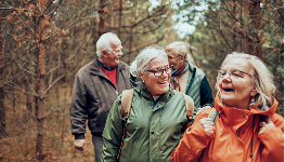Older adults walking together on a wooded path during autumn