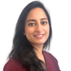Sana Hussain is smiling at the camera with long dark hair and emerald green scrub top on