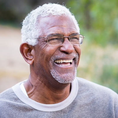 Smiling, black middle aged man with glasses and grey sweatshirt