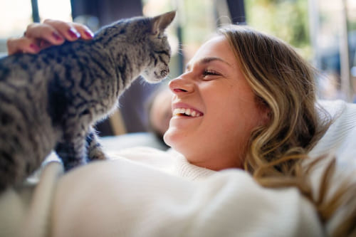 A smiling women sitting on the sofa with her cat