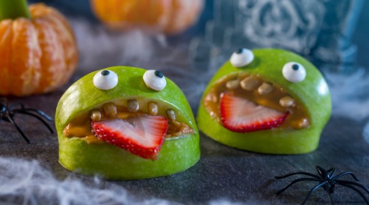 Monsters made of apple slices with strawberry tongues and peanut butter