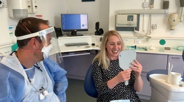 Carly, smiling, looking in the mirror at her results with Bupa Dental Care Gloucester Road 