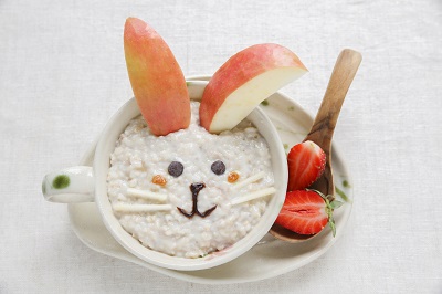Porridge with a bunny face made using apples and blueberries