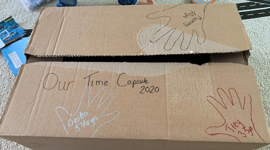 Homemade time capsule using cardboard box with handprints drawn on