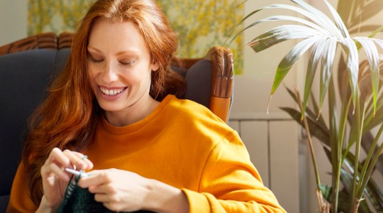 Happy young woman knitting at home 