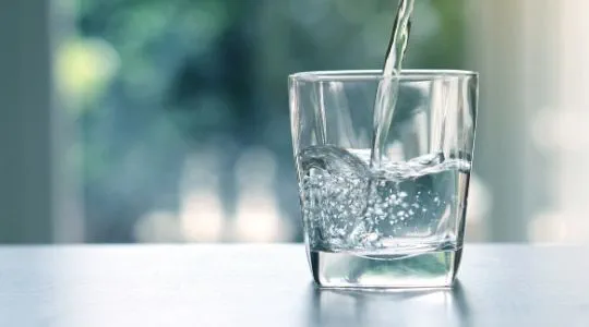 Close up of water being poured into a glass on the kitchen side