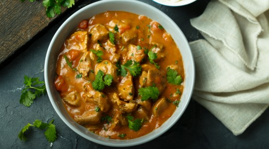 Bowl of chicken curry sprinkled with herbs