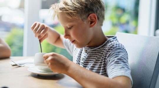 Happy young boy eating soup