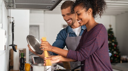 Happy couple cooking spaghetti in pan