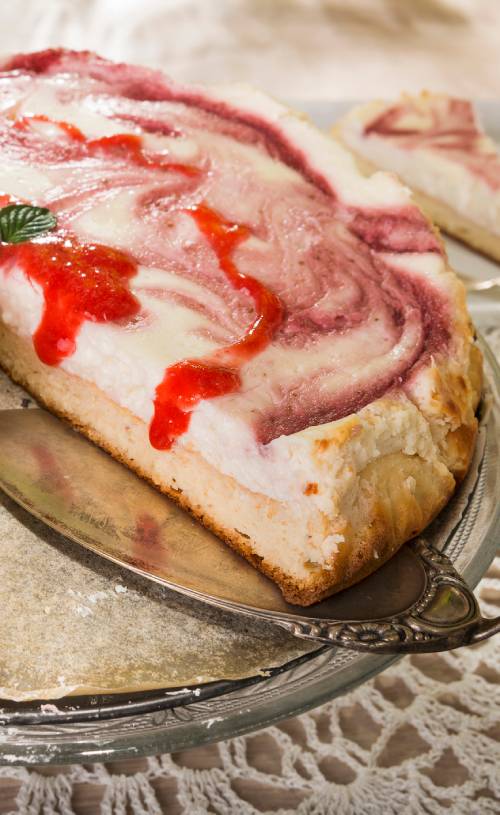 Creamy cheese cake on a nut and coconut base with red berry swirl