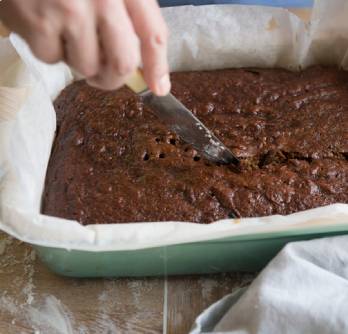 Sugar-free date and chocolate pudding tray bake being cut into portions