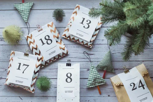 An overhead view of gifts for an advent calendar next to Christmas decorations