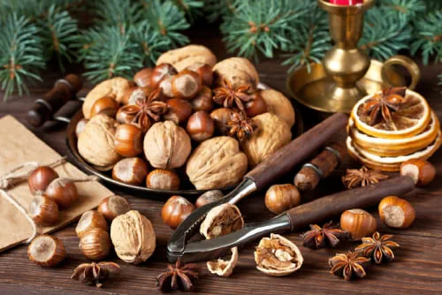 A bowl of nuts and a nutcracker displayed on a wooden background