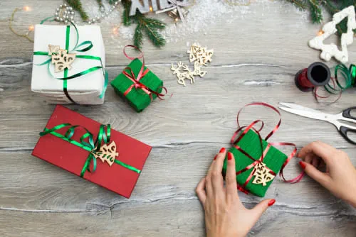 A women's hands wrapping ribbon around a Christmas present