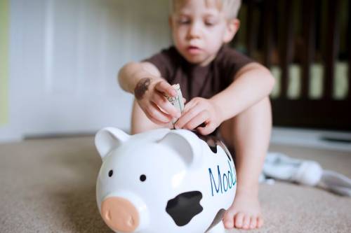Child putting money in a piggy bank
