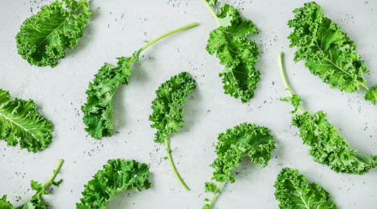 fresh kale leaves laid out on a grey stone worktop