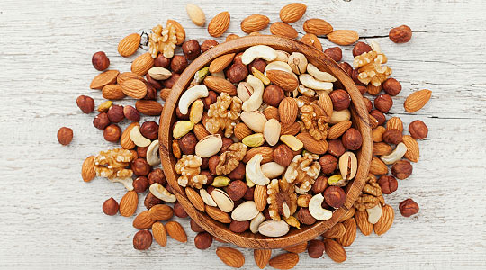 A bowl of mixed nuts including cashews, almonds and peanuts with skin