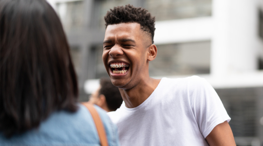 Boy with metal braces laughing with eyes closed 