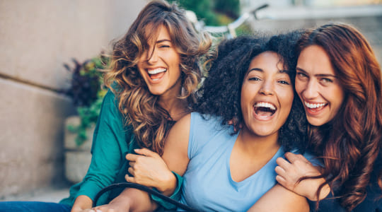 Three women smiling at the camera and hugging