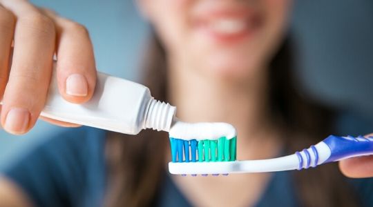 Close up woman putting toothpaste on toothbrush