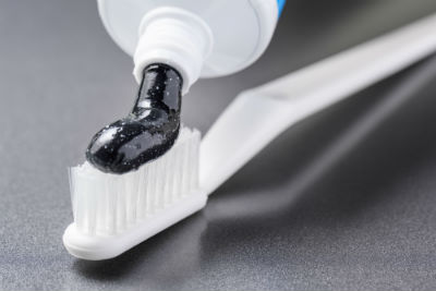 Black charcoal toothpaste being squeezed onto a white toothbrush