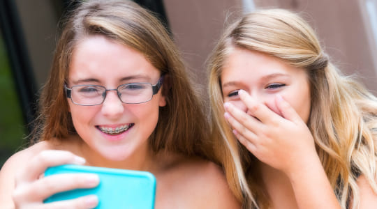 Teenage girl with braces laughing with friend.